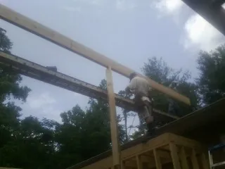 Carpenter setting a ridge beam over a new addition frame — Ice Dam Removal by Roofing Brothers in Kure Beach