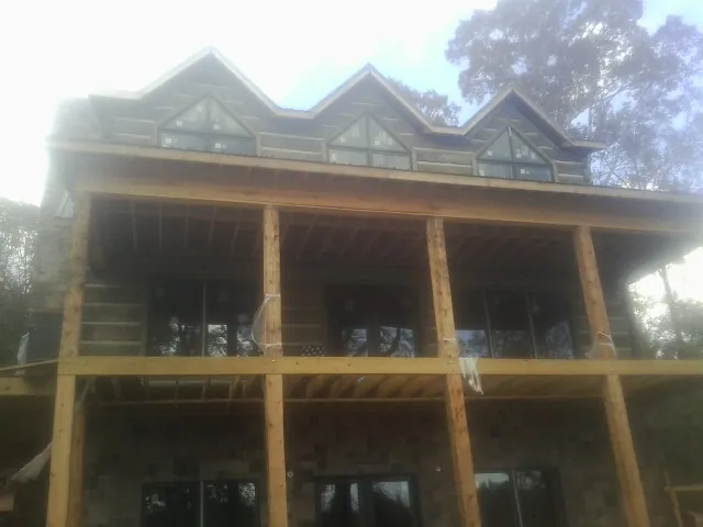 Dormers and porch framing on a large log home under construction — Roof Coating work by our crew in Kure Beach