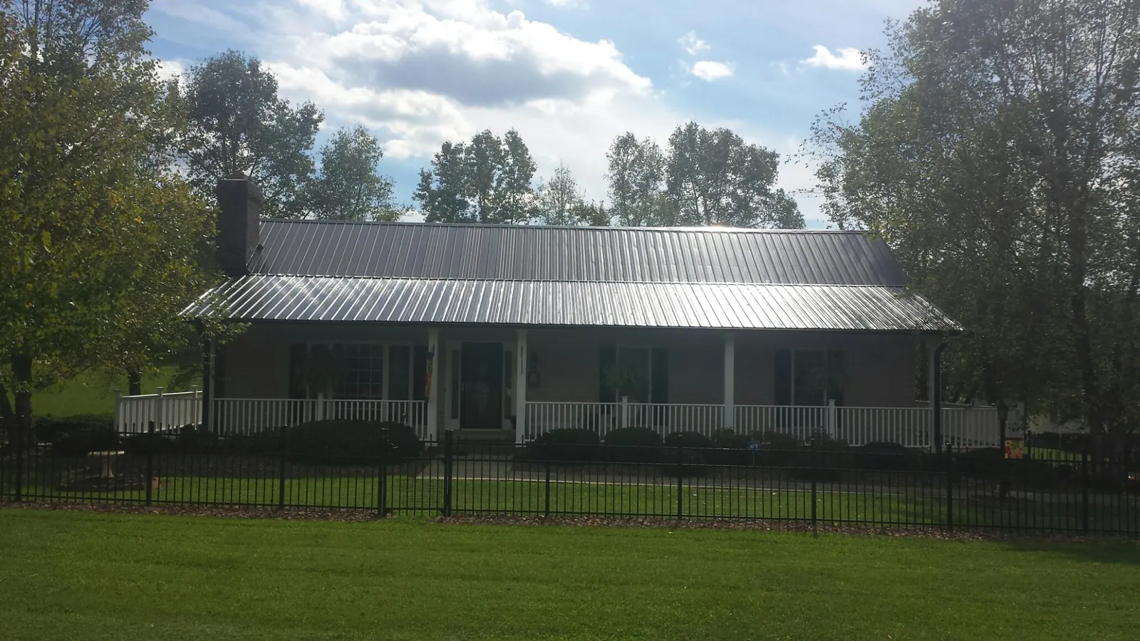 Gray metal roof on a brick ranch with a full width front porch — Gutter Guard Installation work by our crew in Kure Beach