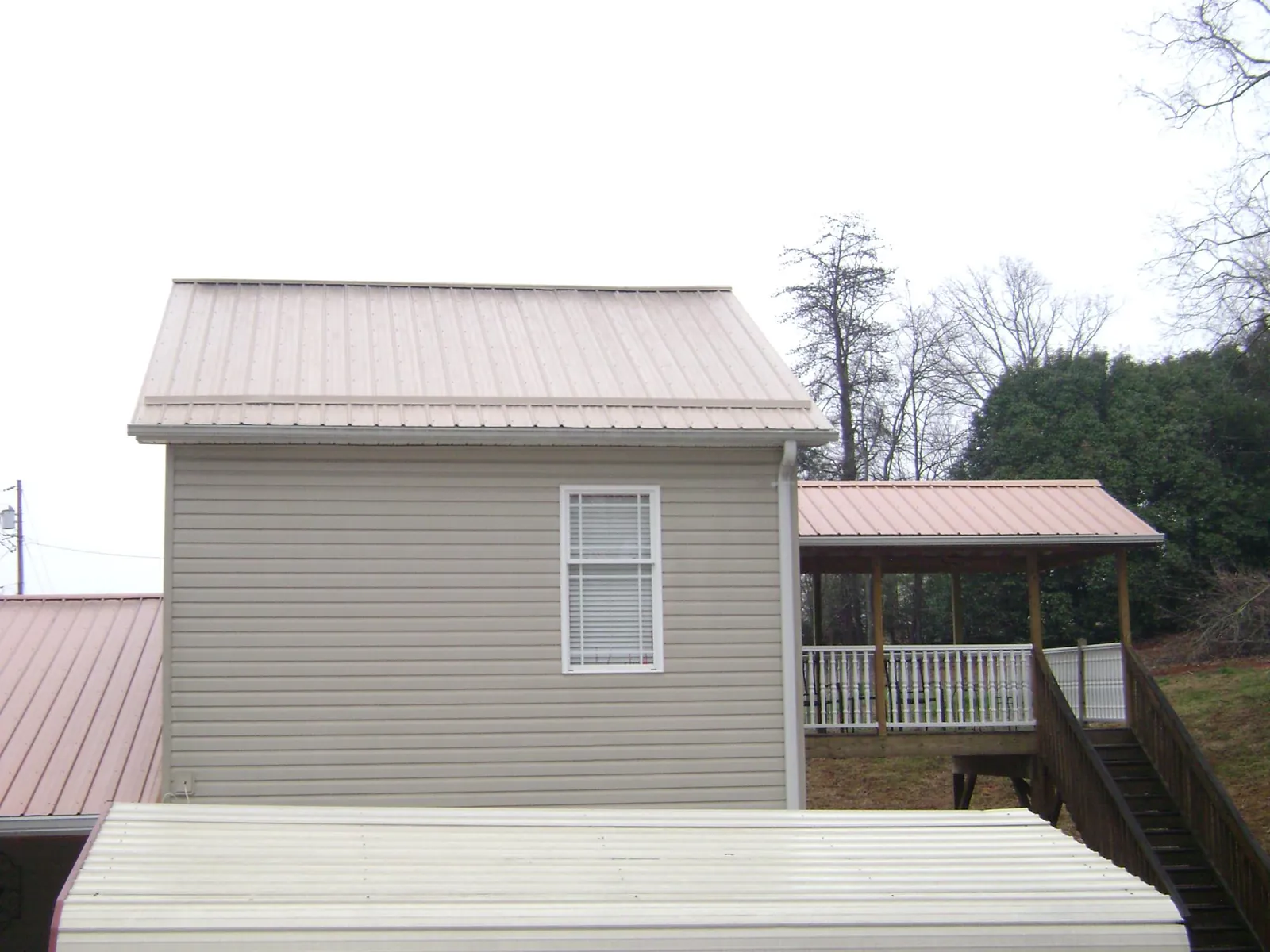 Tan metal roofs on a two story addition and attached porch, from a Roof Replacement job in Kure Beach